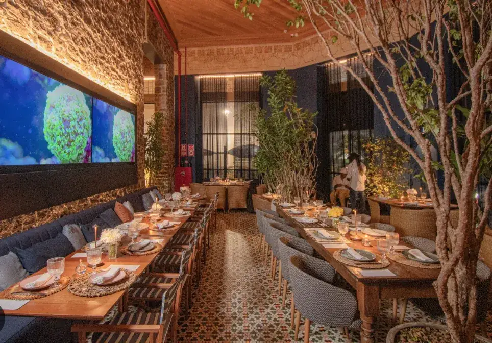 Um dos salões de restaurante do palacete, com piso de ladrilho hidráulico e árvores no ambiente